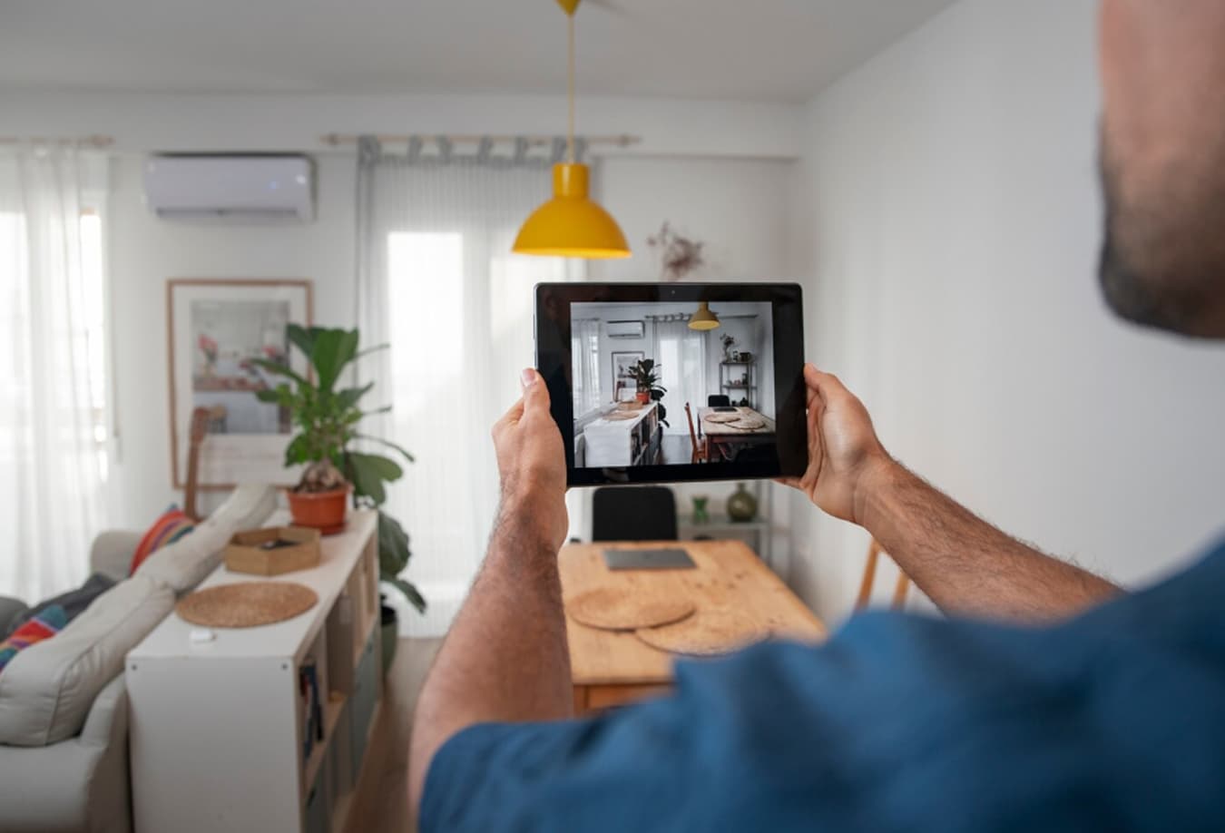 Мужчина наблюдает за своим домом через планшет